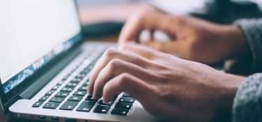 Hands typing at a laptop
